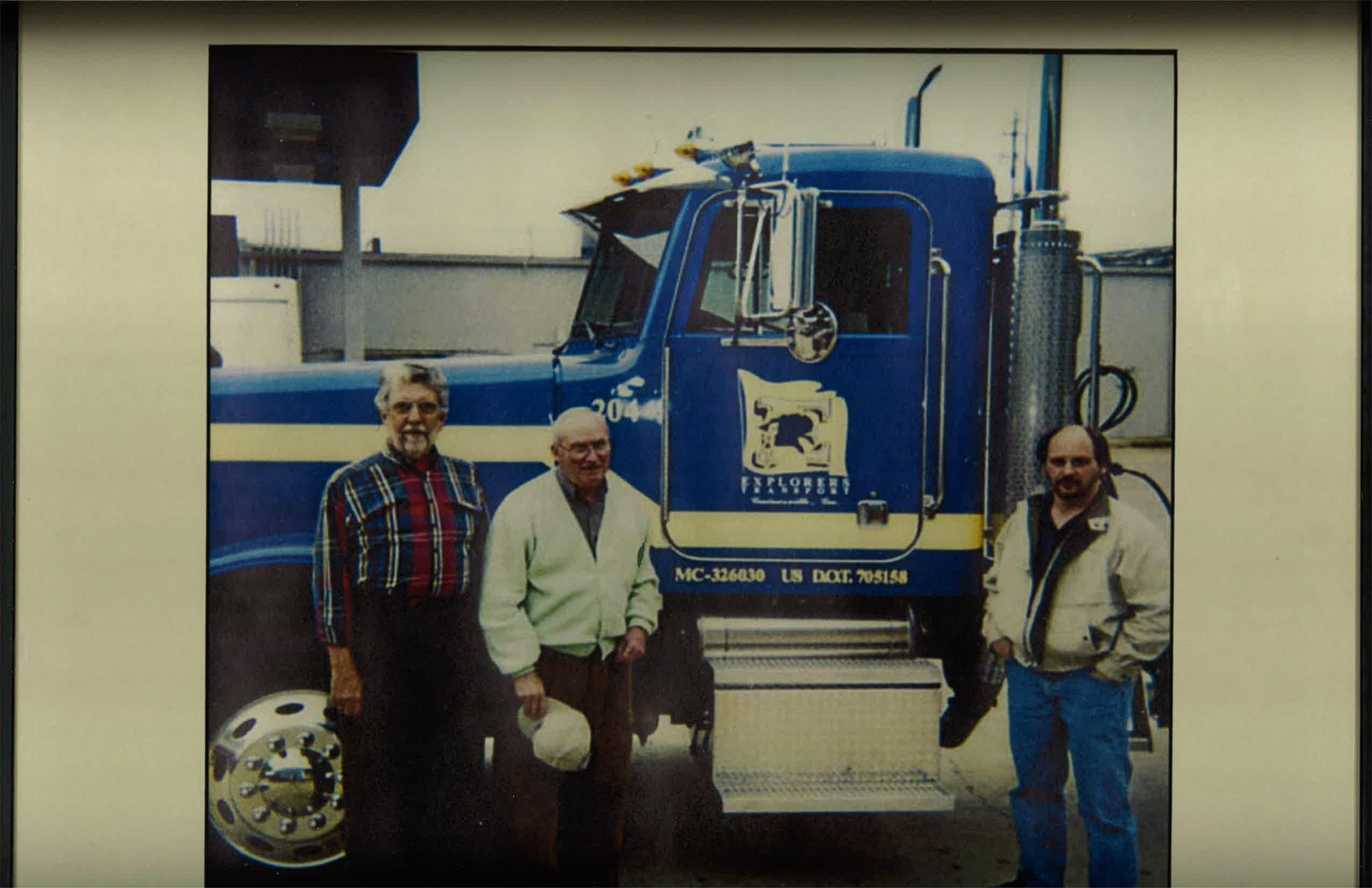 3 men standing in front of Explorers Transport truck